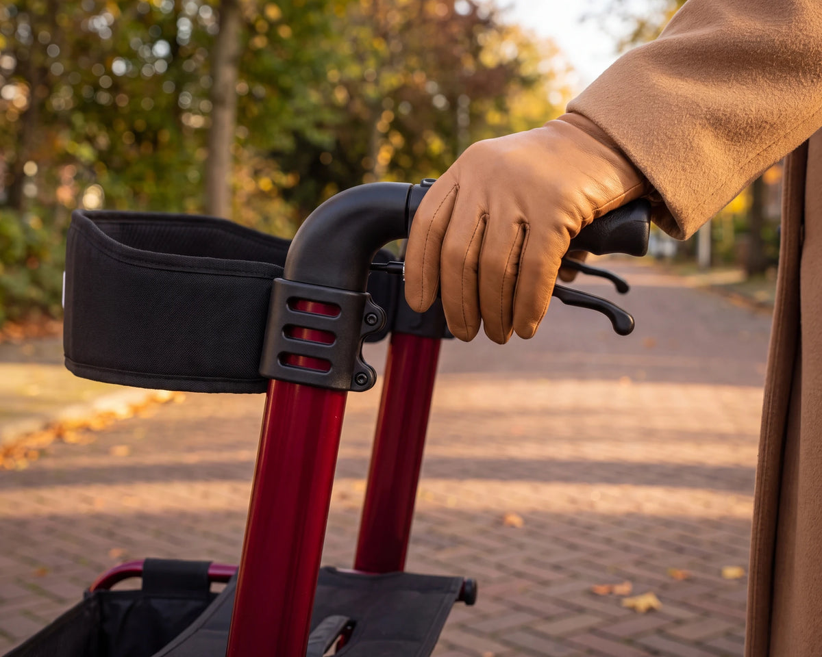 A hand in a leather glove on the handle of the Parvum Luxo in ruby red.