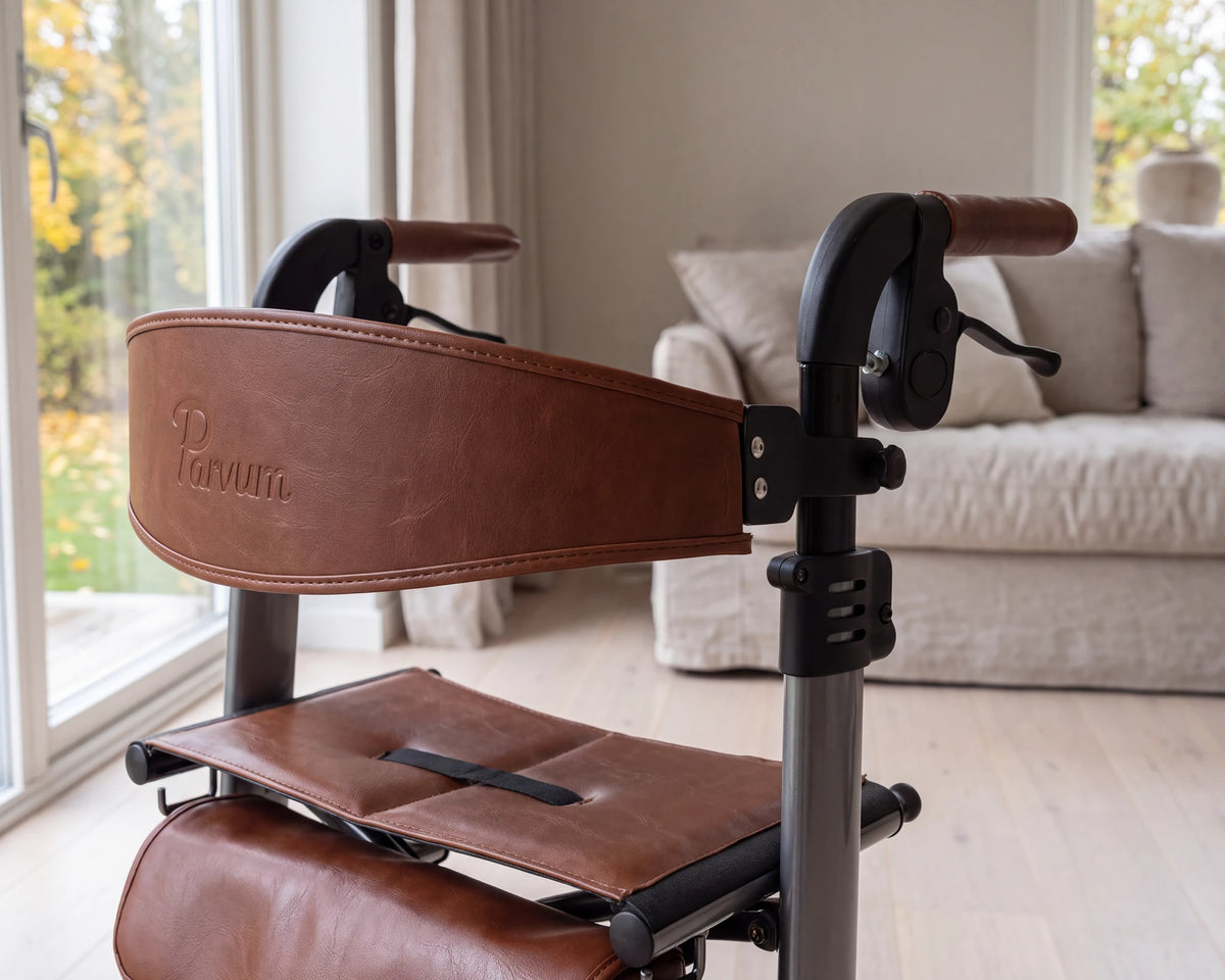 Close-up of the cognac backrest with the embossed Parvum wordmark of the Vesta in silver, in window light.